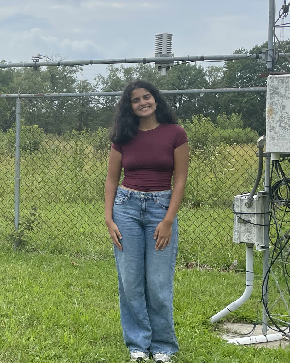Anika smiling beside the instruments of an Illinois Climate Network weather station
